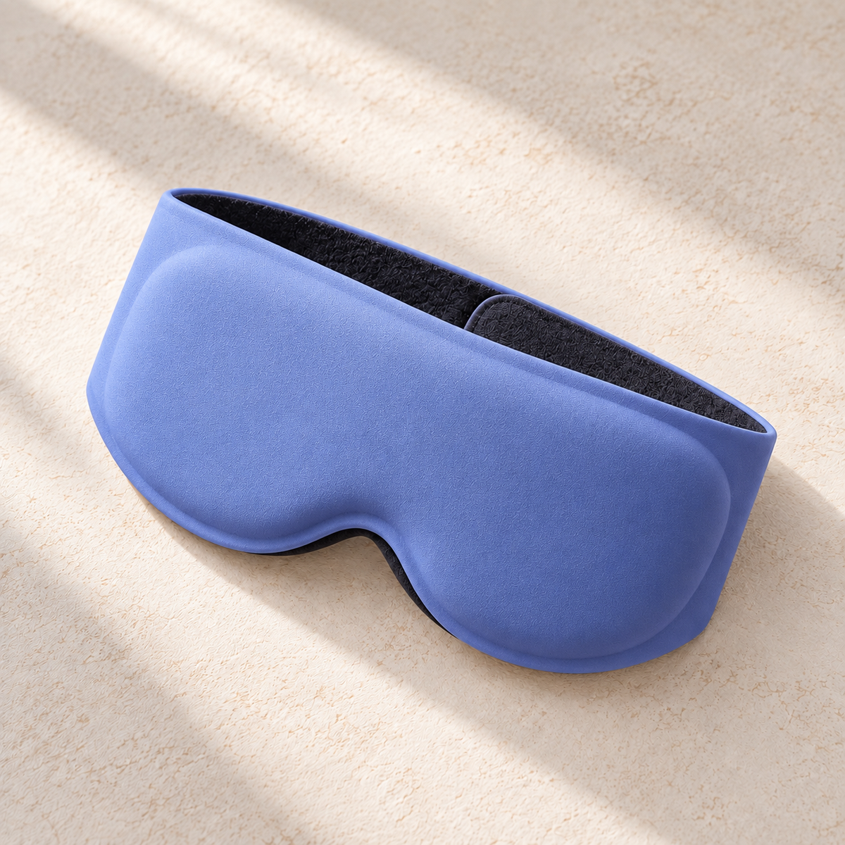 Blue DreamCalm contoured weighted sleep mask on a warm neutral background